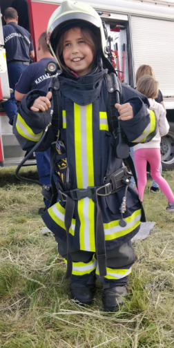 Kislány tűzoltó bevetési kabátban és sisakban