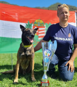 A képen Karma, a serleg és Leczki Sarolta a magyar zászló előtt