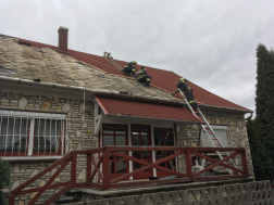 Megbontott tetőt biztosító tűzoltók