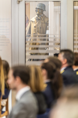 Fotó az ünnepségről, a kép hátterében az aulában lévő kiállításon szereplő, védőálarcos alak