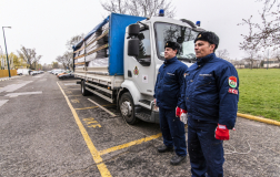 Egyenruhás kollégák állnak a katasztrófavédelem felhajtott ponyvájú teherautója előtt