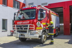 Egy tűzoltó gépjármű egy kollégával teljes tűzóltói felszerelésben.