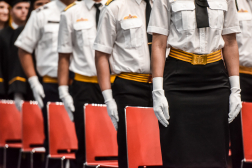 Egyenruhás, fehér kesztyűt viselő hallgatók a diplomaosztón