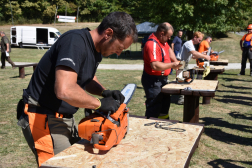 A felállított asztaloknál a versenyzők a motoros fűrészt szerelik