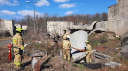 tanácskoznak a függőleges betonhenger mellett a tűzoltók